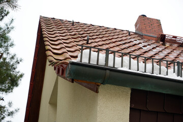 Snow guard metal grid at a house roof with wet snow
