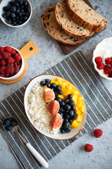 Cottage cheese with berries for breakfast. A plate of cottage cheese with mango, figs and blueberries