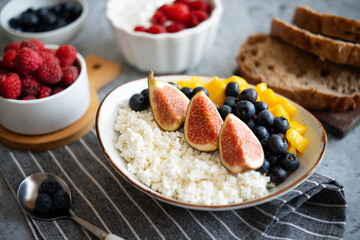 Cottage cheese with berries for breakfast. A plate of cottage cheese with mango, figs and...