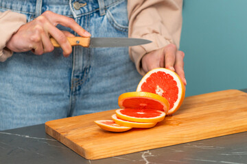 Slicing fresh grapefruit on a wooden cutting board in a modern kitchen