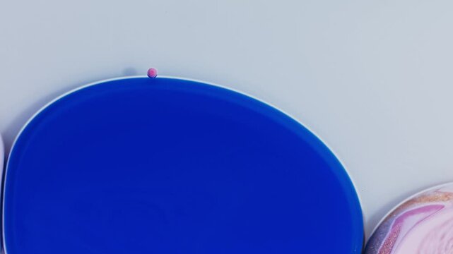 Hypnotic video of close-up acrylic bubbles, blending pink and blue hues on a crisp white background. Perfect for creative projects needing a colorful and artistic visual element.