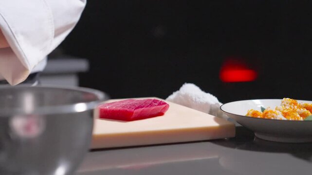 A static shot captures a sushi chef placing fresh cucumber slices on sushi rolls in a bowl, showcasing the final touch of preparation. Ideal for culinary, sushi, and food presentation content.