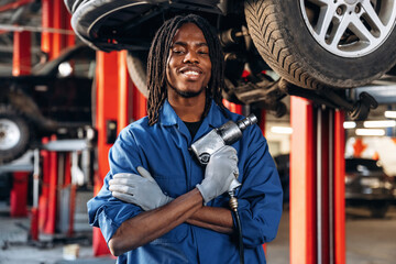 Vehicle is high up, about to change the tire. Male mechanic is with car in garage