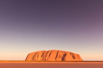 Majestic rock formation under gradient sky, showcasing stunning
