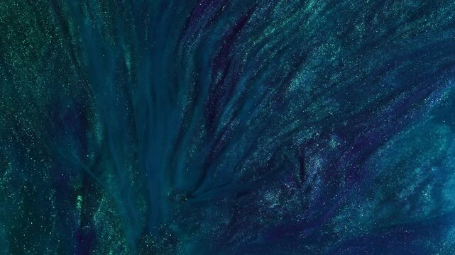 An abstract background of deep blue and green swirls with glitters. The colors blend and flow together like liquid or particles in motion. This combination creates a sense of depth.