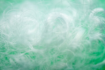 Extreme macro of polyester stable fiber on green background. Selective focus, shallow depth of field. Abstract dreamy background