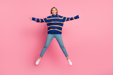 Fashionable young woman in a striped sweater bouncing against a pink background