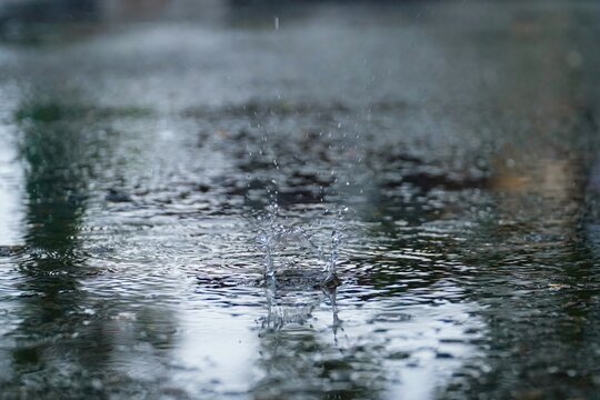 Drops of rain that fall on the asphalt when it rains. close-up rain drops. Drops of heavy rain in a puddle on the asphalt road. A Stream of water that floods all around. Rain drop splash.