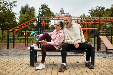 Obraz premium Mature couple enjoys playful laughter together in a park during a sunny afternoon