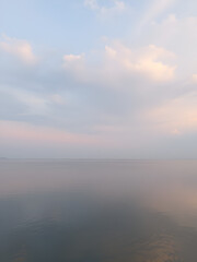 Fototapeta premium Tranquil Lake and Serene Sky with Gentle Clouds in Soft Pastel Colors