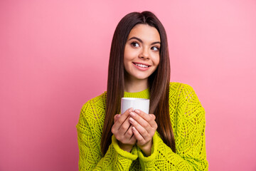 Young woman enjoying warm drink and radiating positive vibes in trendy knitwear against vivid pink...