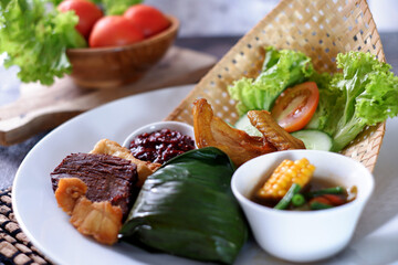 Nasi Timbel Set Meal from  West Java Indonesia, is steamed rice wrap in banana leaf accompanied with chicken, fried tofu,salty fish,tempeh,chilli paste and various raw vegetables. Top view 1