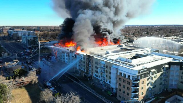 Drone view, slowly orbiting an apartment building that's ablaze with fire and smoke