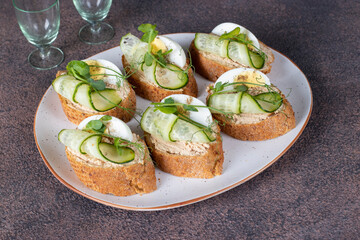 Bruschetta with tuna pate, egg and cucumber on white plate