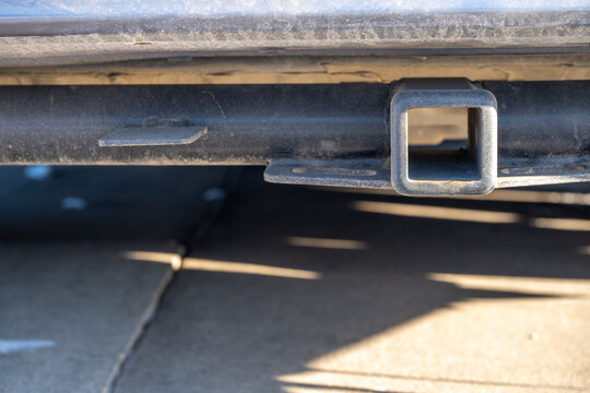 Selective focus on the front end of an empty square hitch receiver on the back end of a vehicle. 