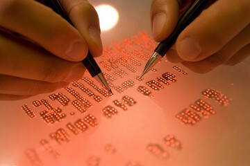 Hands engaged in writing binary code on a transparent surface illuminated by red light
