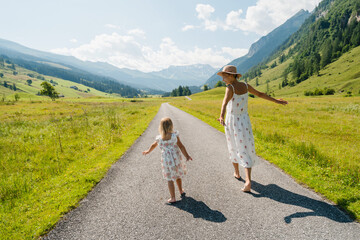 Mother and daughter in green nature. Healthy family outdoors. Woman with little girl in meadow.