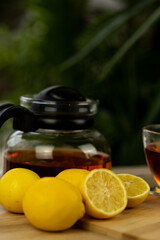 Glass cup of tea, teapot, sliced lemons on the table. Kettle with tea. Lemon tea