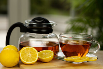 Glass cup of tea, teapot, sliced lemons on the table. Kettle with tea. Lemon tea