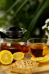 Glass cup of tea, teapot, sliced lemons on the table. Kettle with tea. Lemon tea