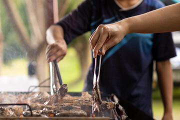 Barbecued meat is grilled on charcoal stove with various ingredients. Meat and various ingredients are grilled on charcoal stove be cooked as steak and barbecue during friends camping celebrate succes