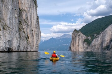 A kayaker paddling across a remote mountain lake, with towering cliffs on both sides