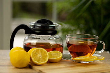 Glass cup of tea, teapot, sliced lemons on the table. Kettle with tea. Lemon tea
