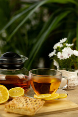 Glass cup of tea, teapot, sliced lemons on the table. Kettle with tea. Lemon tea