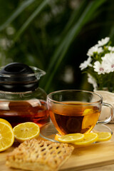 Glass cup of tea, teapot, sliced lemons on the table. Kettle with tea. Lemon tea