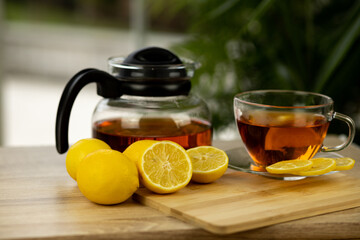 Glass cup of tea, teapot, sliced lemons on the table. Kettle with tea. Lemon tea