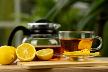 Glass cup of tea, teapot, sliced lemons on the table. Kettle with tea. Lemon tea