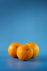 Three vibrant oranges on a blue background highlighting their texture and color