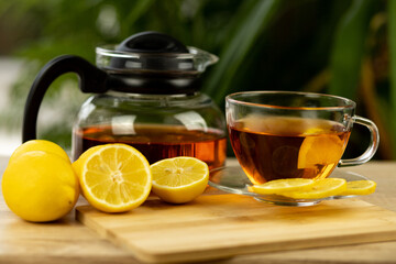 Glass cup of tea, teapot, sliced lemons on the table. Kettle with tea. Lemon tea