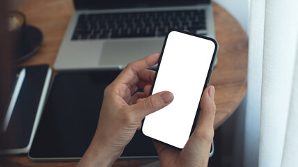 Mockup, Woman using, finger touching on mobile phone with blank white screen while online working on laptop at coffee shop. Woman using smartphone, mockup for online marketing, closeup