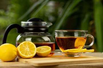 Glass cup of tea, teapot, sliced lemons on the table. Kettle with tea. Lemon tea