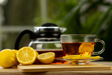 Glass cup of tea, teapot, sliced lemons on the table. Kettle with tea. Lemon tea