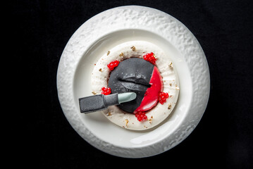 A creatively plated dessert features a unique combination of textures and colors. dish includes a circular meringue base topped with vibrant fruit puree, edible gold flakes, and an chocolate sculpture