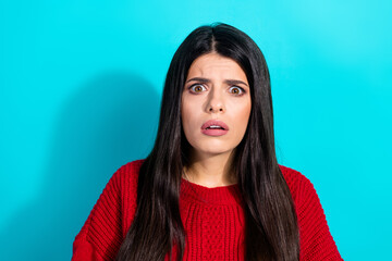 Fototapeta premium Portrait of a young woman in a red sweater exuding curiosity against turquoise blue background.