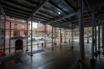 Passing under scaffolding near buildings on a street in New York