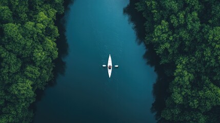 drone shot of person kayaking through narrow river surrounded by dense forest
