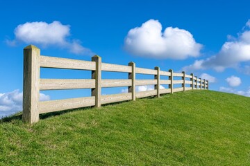 Fototapeta premium A single wooden fence running along the crest of a quiet hill, creating a peaceful scene