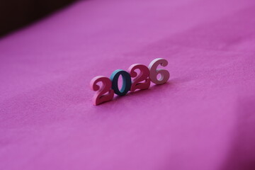 Una toma de cerca del numero dos mil veinte seis en un fondo fucsia 