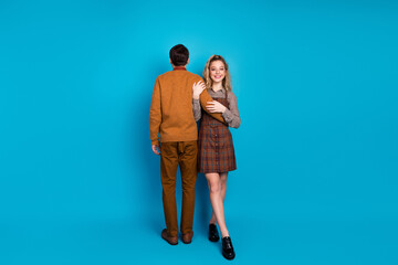 Young Couple Standing Together Against Blue Background in Retro Style Outfits