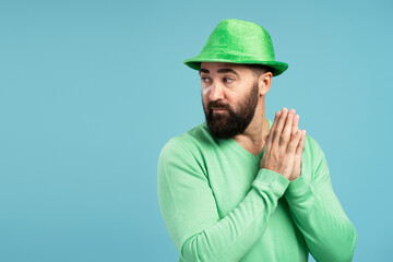 Bearded man wearing green St. Patrick's Day hat scheming something
