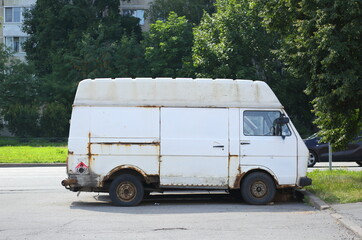 An old rusty white minibus is parked in the courtyard of a residential building, Iskrovsky Prospekt, St. Petersburg, Russia, July 26, 2024