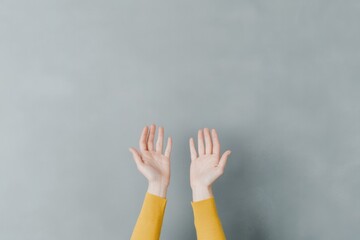 minimalistic stock photo of hands raised in front of textured gray wall fingers splayed open