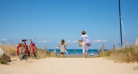 Une femme et une petite fille allant &agrave; la plage pendant les vacances au bord de la mer en &eacute;t&eacute;.