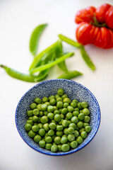 Bol de petit pois vert et tomate fraiche dans une cuisine pour la réalisation d'une recette gourmande.