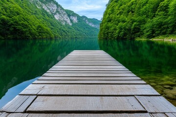 Naklejka premium A wooden dock extending into a still lake, surrounded by dense forest and a mirror-like reflection