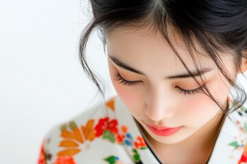 Fototapeta premium Japanese woman looking down with a sad look, white background nearby.